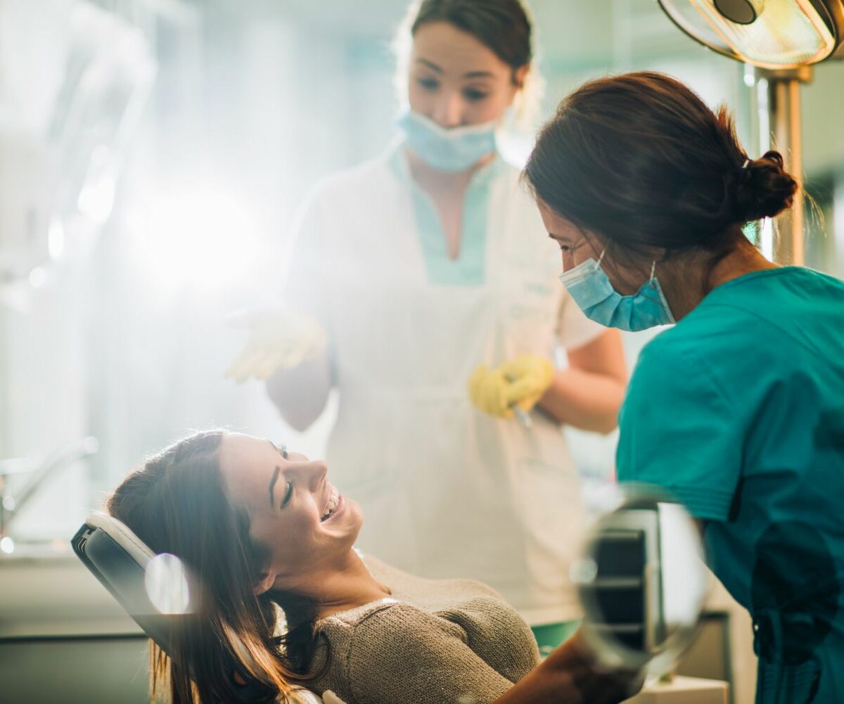 Smiling woman sitting in dentist chair and talking to her dentist before teeth examination.